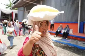 DOKUMENTASI - Seorang ibu menjunjung bantuan pangan beras 10 kilogram (kg) sambil mengacungkan jempol.* ANTARA/HO-Humas Bapanas
