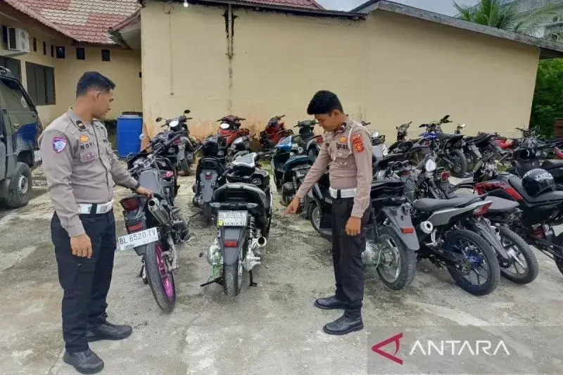 Personel Satlantas Polres Aceh Barat memperlihatkan puluhan sepeda motor yang diamankan dari sejumlah lokasi balapan liar, yang diamankan di Kompleks Satlantas Polres Aceh Barat di Meulaboh, Selasa (7/1/2025). (ANTARA/HO)