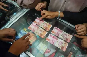Petugas Bank Indonesia (BI) menunjukkan perbedaan uang asli (kanan) dan uang yang diduga palsu (kiri) saat sosialisasi keaslian uang rupiah di Pasar Bu'rung-bu'rung, Kabupaten Gowa, Sulawesi Selatan, Selasa (31/12/2024). ANTARA FOTO/Hasrul Said/Spt.
