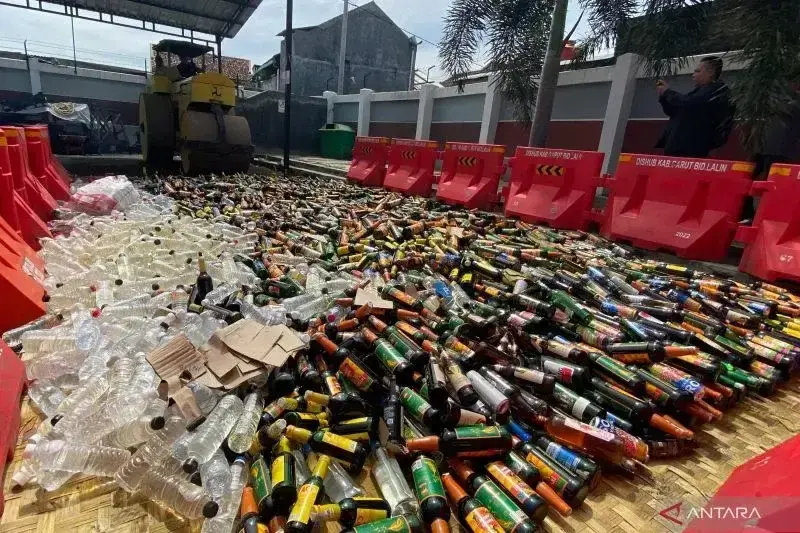 Petugas memusnahkan minuman keras hasil razia dan tindak pidana ringan (tipiring) di tempat pemusnahan barang bukti Kantor Kejaksaan Negeri Kabupaten Garut, Jawa Barat. (ANTARA/Feri Purnama)