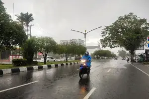 Dokumentasi - Warga melintasi jalan raya saat hujan mengguyur wilayah Kota Palangka Raya. ANTARA/Rendhik Andika