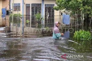 Ilustrasi - Seorang warga melintas di samping rumahnya yang terendam banjir di Desa Napai, Woyla Barat, Aceh Barat, Aceh, Minggu (17/11/2024). (ANTARA FOTO/Syifa Yulinnas)
