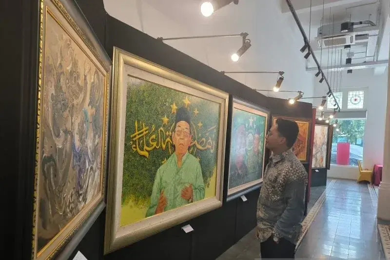Seorang pengunjung menikmati lukisan yang dipamerkan di Indonesia Painting Exhibition 2025 di Antara Heritage Center Pasar Baru, yang digelar pada 12 hingga 18 Maret 2025. (ANTARA/Sigit Pinardi)