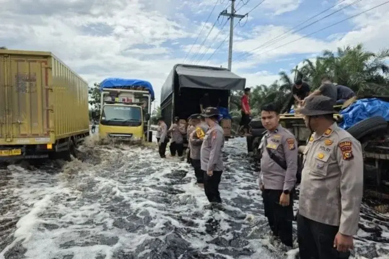Banjir di Jalan Lintas Timur (Jalintim) di Kecamatan Pangkalan Kerinci, Pelalawan menyebabkan kendaraan sulit melewati genangan akibat luapan Sungai Kampar ini. (ANTARA/HO-Polsek Pangkalan Kerinci))