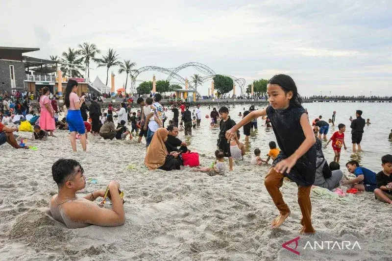 Pengunjung membenamkan tubuhnya dalam pasir di Pantai Lagoon Ancol, Jakarta, Selasa (1/4/2025). PT Pembangunan Jaya Ancol Tbk menargetkan sebanyak 70 ribu pengunjung per hari saat periode libur Lebaran 2025. ANTARA FOTO/Sulthony Hasanuddin/nym.